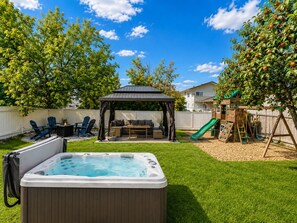 A backyard with a hot tub, patio furniture, a play structure, and a covered seating area. - 5-Min Walk to WEM Hot Tub and A/C (Edmonton)