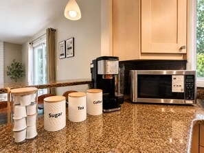 A kitchen with a coffee maker, a microwave, and labeled containers for sugar, tea, and coffee. - 5-Min Walk to WEM Hot Tub and A/C (Edmonton)