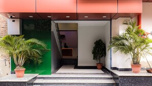 A hotel entrance with a reception desk, a staircase leading to the interior, and potted plants. - Hotel Vaikunth (Sahibganj)