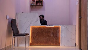 A reception desk with a marble top, a black chair, and a shelf with decorative items. - Hotel Vaikunth (Sahibganj)