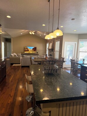 A spacious kitchen with a large island, wooden flooring, and pendant lighting. - Spacious 7-bedroom house in beautiful North Salt Lake (North Salt Lake)