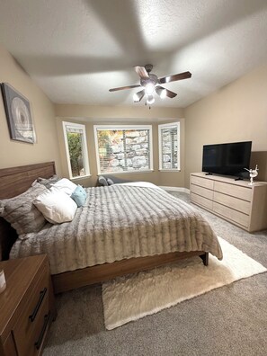 A bedroom with a bed, a dresser, a television, and a ceiling fan. - Spacious 7-bedroom house in beautiful North Salt Lake (North Salt Lake)