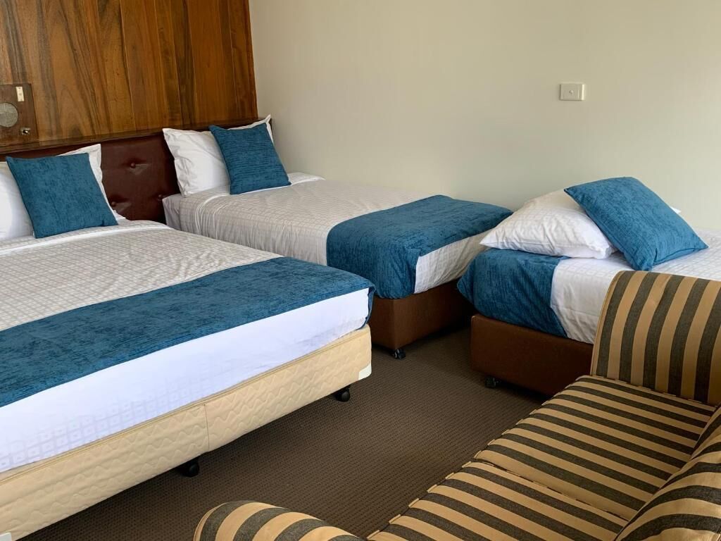 Une chambre d’hôtel avec deux lits, un canapé et une tête de lit en bois.