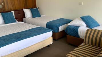 Une chambre d’hôtel avec deux lits, un canapé et une tête de lit en bois.