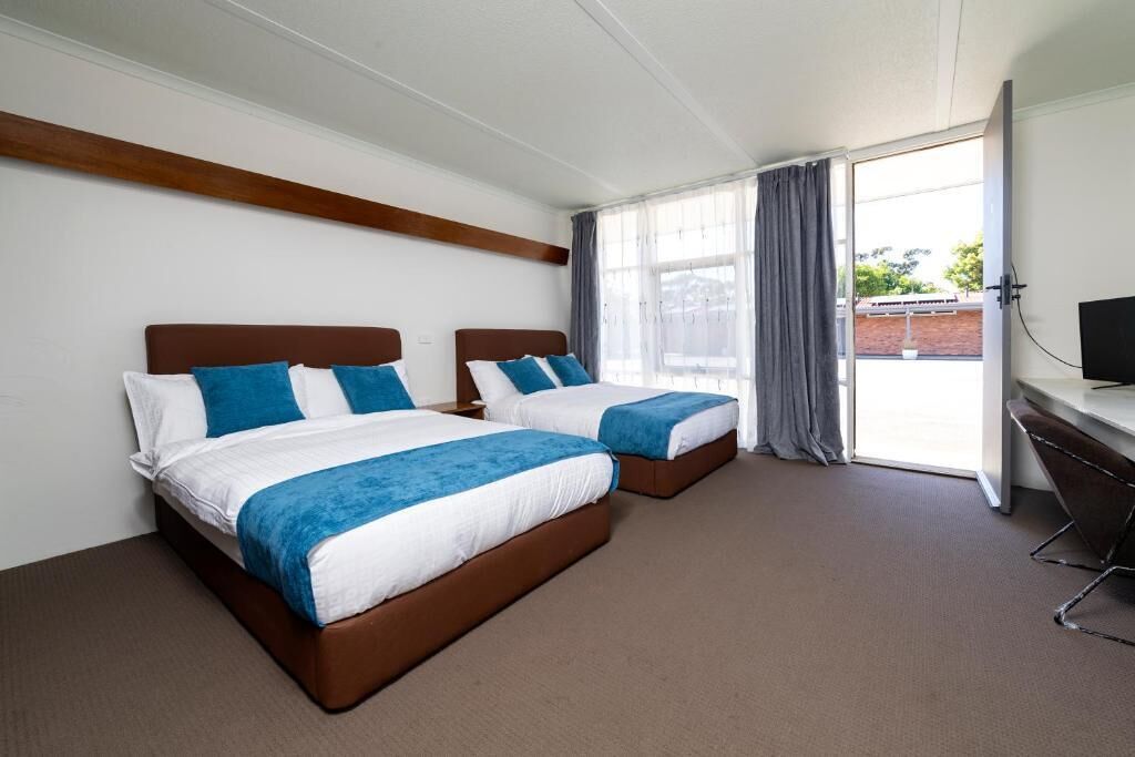 Een hotelkamer met twee bedden, een bureau en een groot raam.