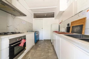 A kitchen with white cabinets, a gas stove, an oven, a microwave, and a sink.