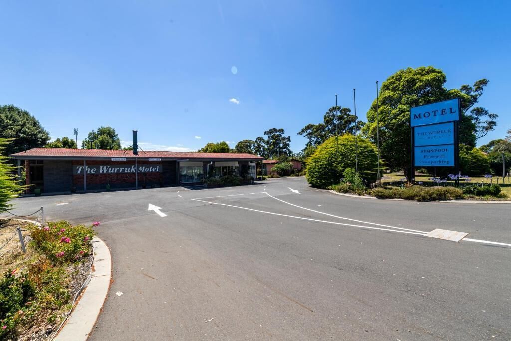 The Warruk Motel with a clear road layout, a signboard, and surrounding greenery.