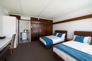 Une chambre d’hôtel avec deux lits, un bureau et une petite kitchenette.