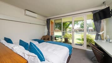 Ein Hotelzimmer mit einem Bett, einem Schreibtisch, einem Fernseher und einer Glastür, die auf einen Balkon führt.