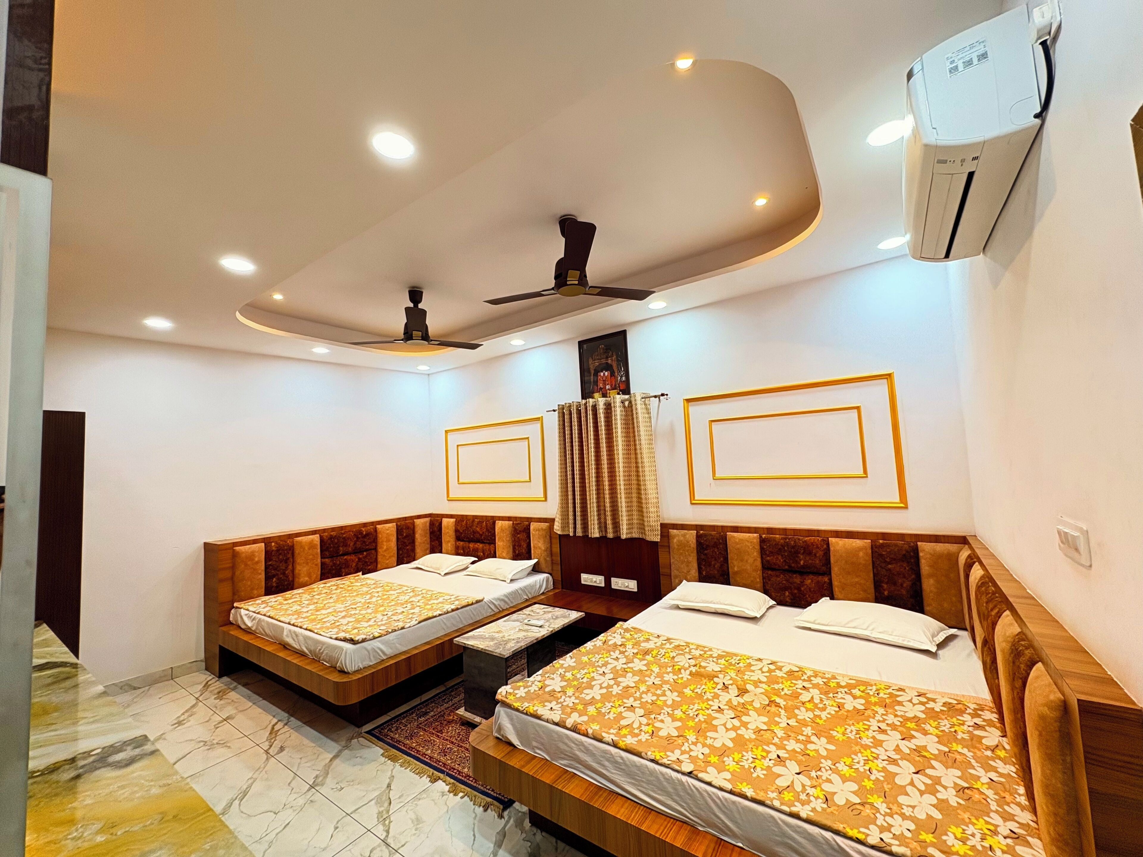 Habitación de hotel con dos camas, ventilador de techo, luces empotradas y equipo de aire acondicionado.