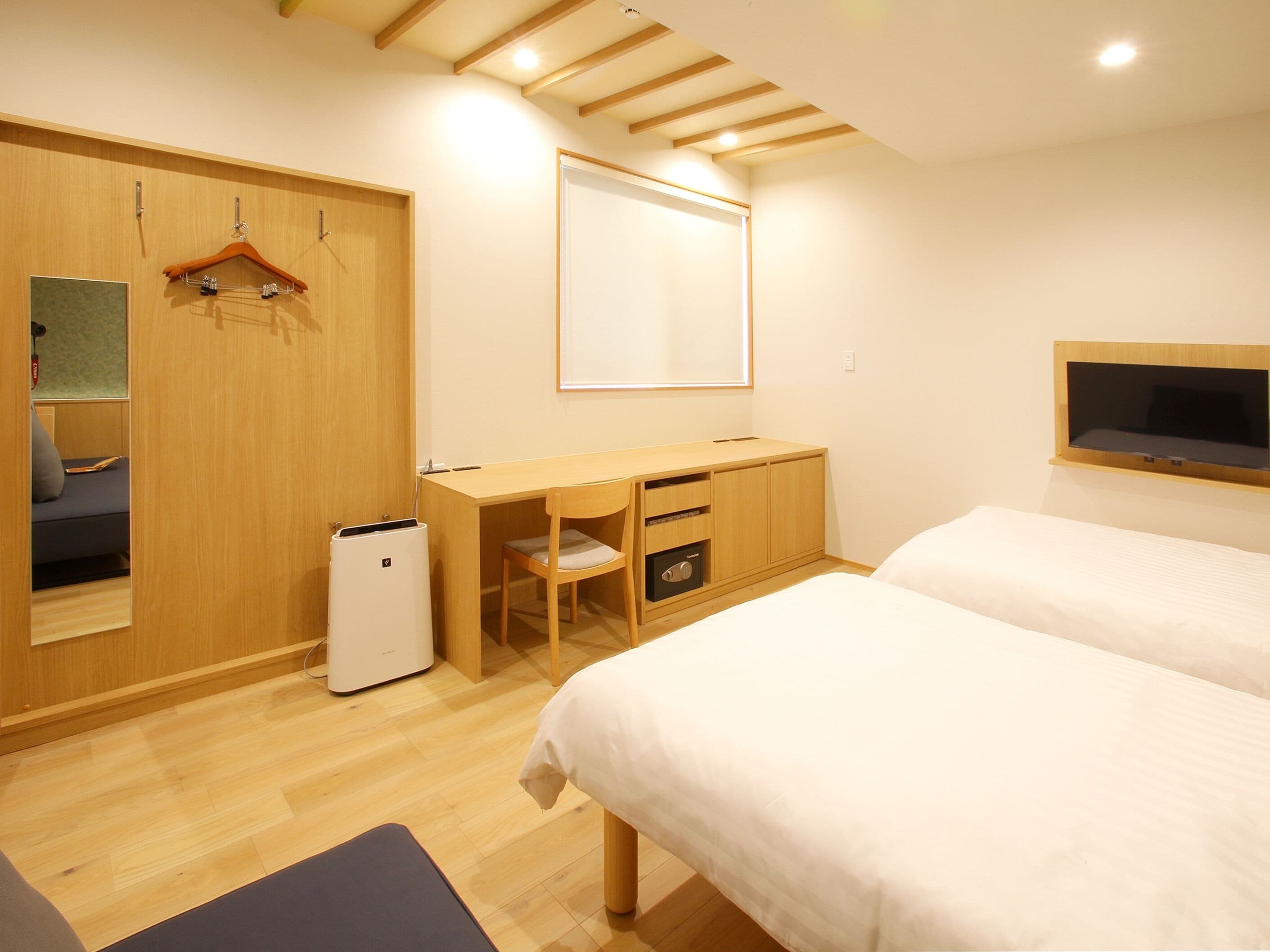 Ein Schlafzimmer mit einem Bett, einem Schreibtisch, einem Stuhl, einem Kleiderschrank und einem Fernseher.