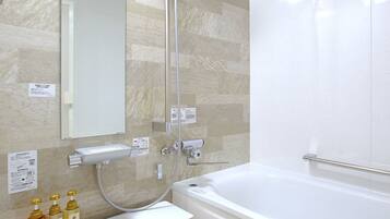 A modern bathroom with a bathtub, a shower, a sink, and a mirror. There are toiletries on the sink counter.