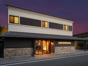 A modern two-story building with a stone facade and a flat roof.