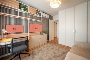 Ein modernes Hotelzimmer mit Schreibtisch, Stuhl, Kleiderschrank und einem Bett.