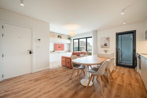 Une cuisine moderne avec des meubles blancs, un canapé rose et une table à manger avec des chaises.