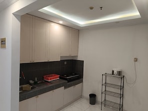 A compact kitchen with a black countertop, beige cabinets, and a black trash bin. - Spacious 3-bedroom apartment with AC in serene Jogja (Jogja)