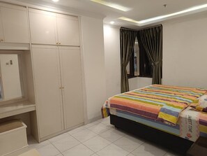 Ein Schlafzimmer mit einem Bett, einem Kleiderschrank und einem Fenster mit Vorhängen.