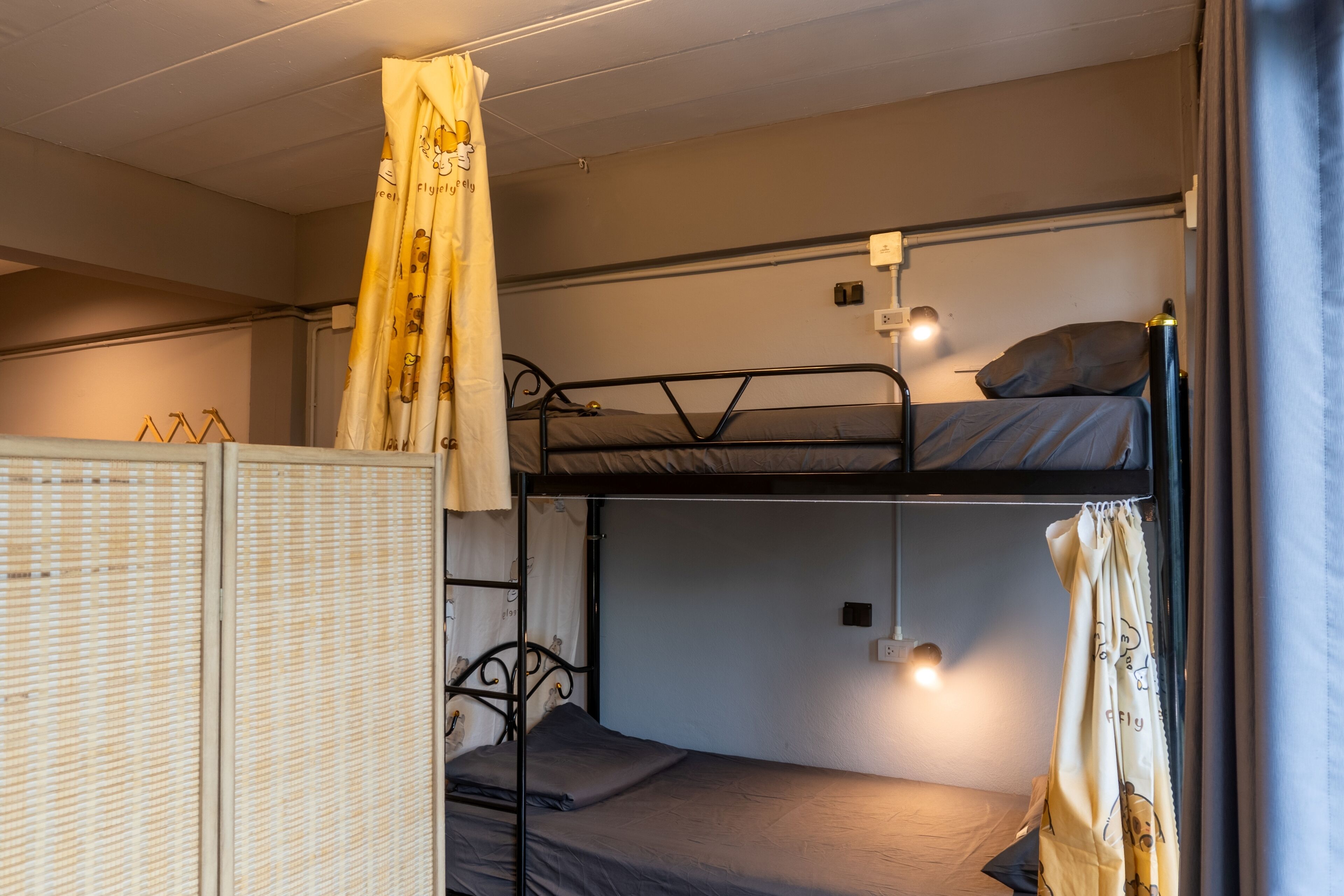A bunk bed room with a wardrobe, a curtain, and a wall socket.