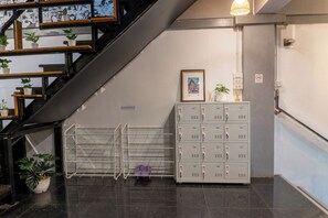 Una escalera con barandilla de metal, un zapatero en la pared y una serie de taquillas.