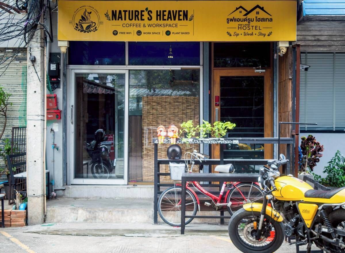 A storefront with a sign for 'Nature's Heaven Coffee & Workspace' and a 'Hostel' sign in another language.