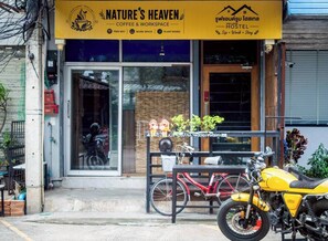 A storefront with a sign for 'Nature's Heaven Coffee & Workspace' and a 'Hostel' sign in another language. - Nature's Heaven Hostel (Chiang Mai)