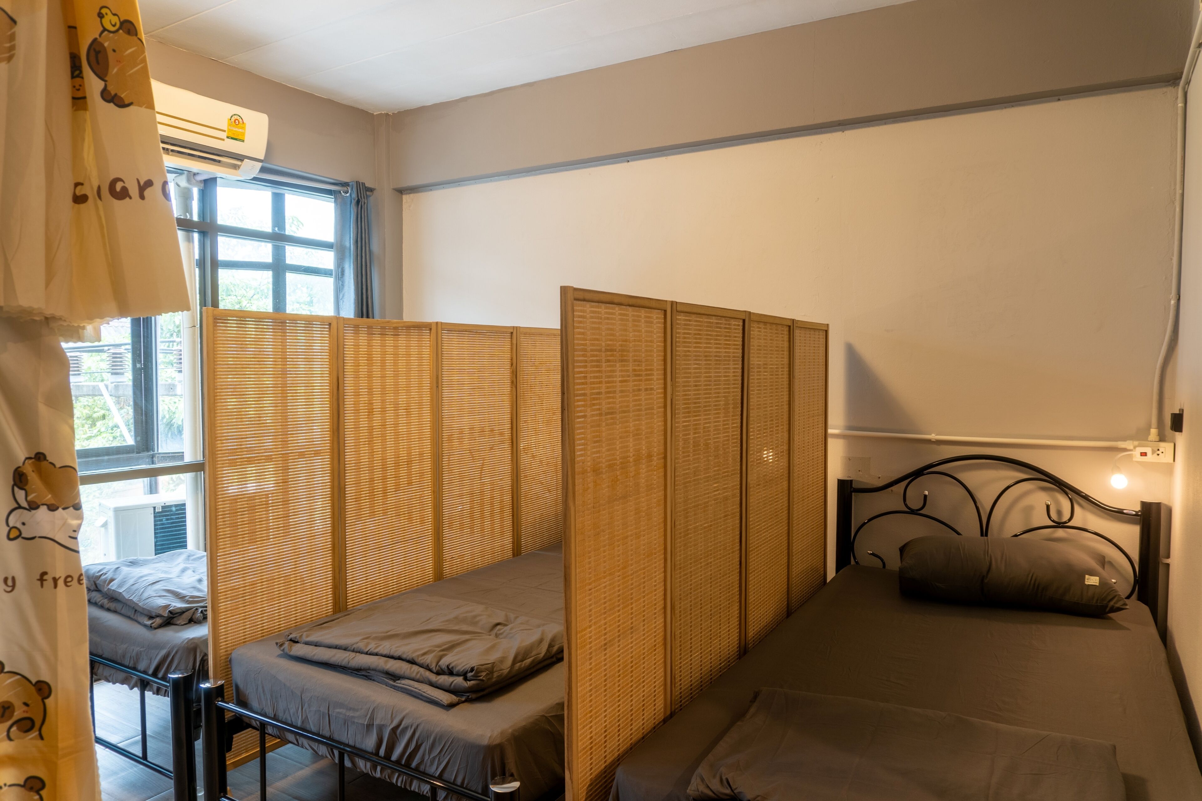 Quarto individual com cama, janela e divisória.