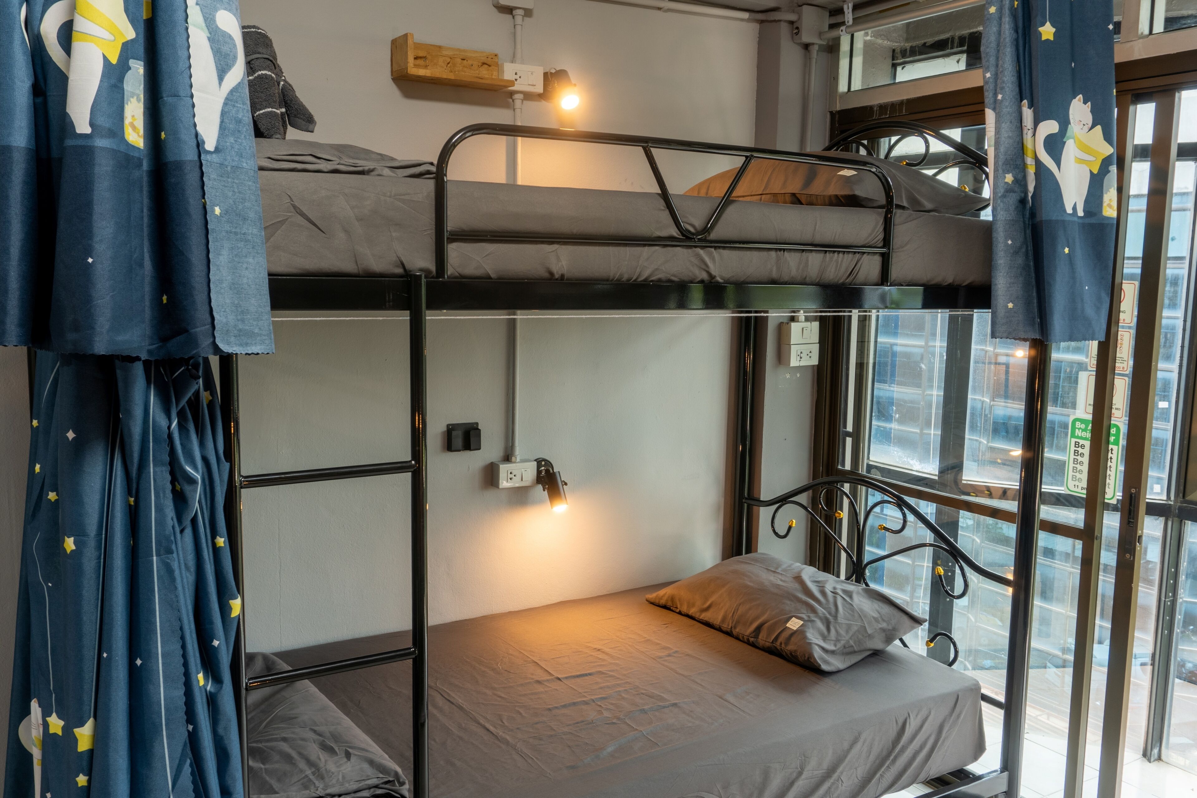 Ein Schlafzimmer mit Etagenbetten, einem Fenster, Vorhängen und einer Nachttischlampe.