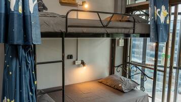 Ein Schlafzimmer mit Etagenbetten, einem Fenster, Vorhängen und einer Nachttischlampe.
