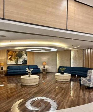 Een moderne woonkamer met twee banken, ronde salontafels en een groot abstract schilderij aan de muur.