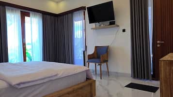 Habitación de hotel con cama, televisor montado en la pared, una silla y una puerta.