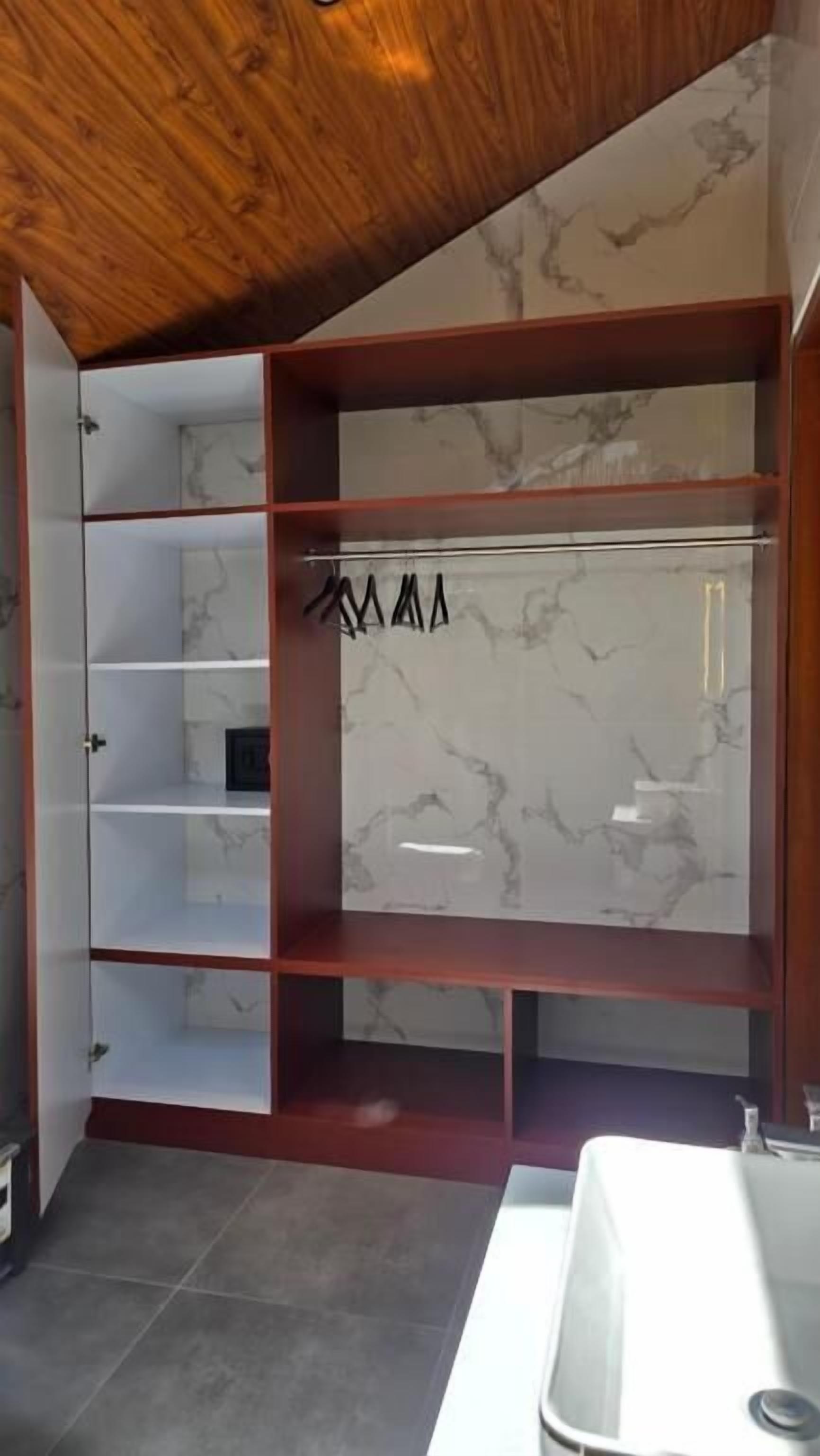 Un baño moderno con salpicadero de mármol, estantes de madera y un lavabo blanco.