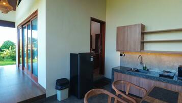 Una cocina compacta con refrigerador, pileta y alacenas de madera.