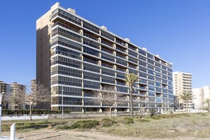 A multi-story hotel with a modern architectural design, featuring balconies on each floor. - VACACIONES FRENTE AL MAR - Only families (Playa de Gandía)