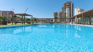 A swimming pool with a tiled floor, surrounded by benches and a pergola structure. - VACACIONES FRENTE AL MAR - Only families (Playa de Gandía)