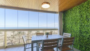 A wooden table with chairs in a room with a large window overlooking a beach. - VACACIONES FRENTE AL MAR - Only families (Playa de Gandía)