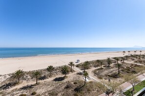 A beach with a clear sky, sandy shore, and palm trees. - VACACIONES FRENTE AL MAR - Only families (Playa de Gandía)
