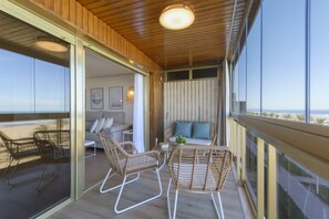 A balcony with wicker furniture, a sofa, and a view of the beach. - VACACIONES FRENTE AL MAR - Only families (Playa de Gandía)