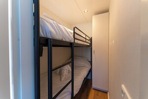 Una cama litera con un armario pequeño y una puerta.