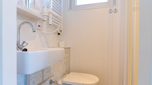 A compact bathroom with a white sink, a toilet, a mirror, and a window above the toilet. - Houseboat With Rooftop Terrace (Wolphaartsdijk)