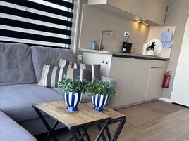 Una cocina moderna con un sofá gris, cojines a rayas y dos jarrones a rayas sobre una mesa de madera.