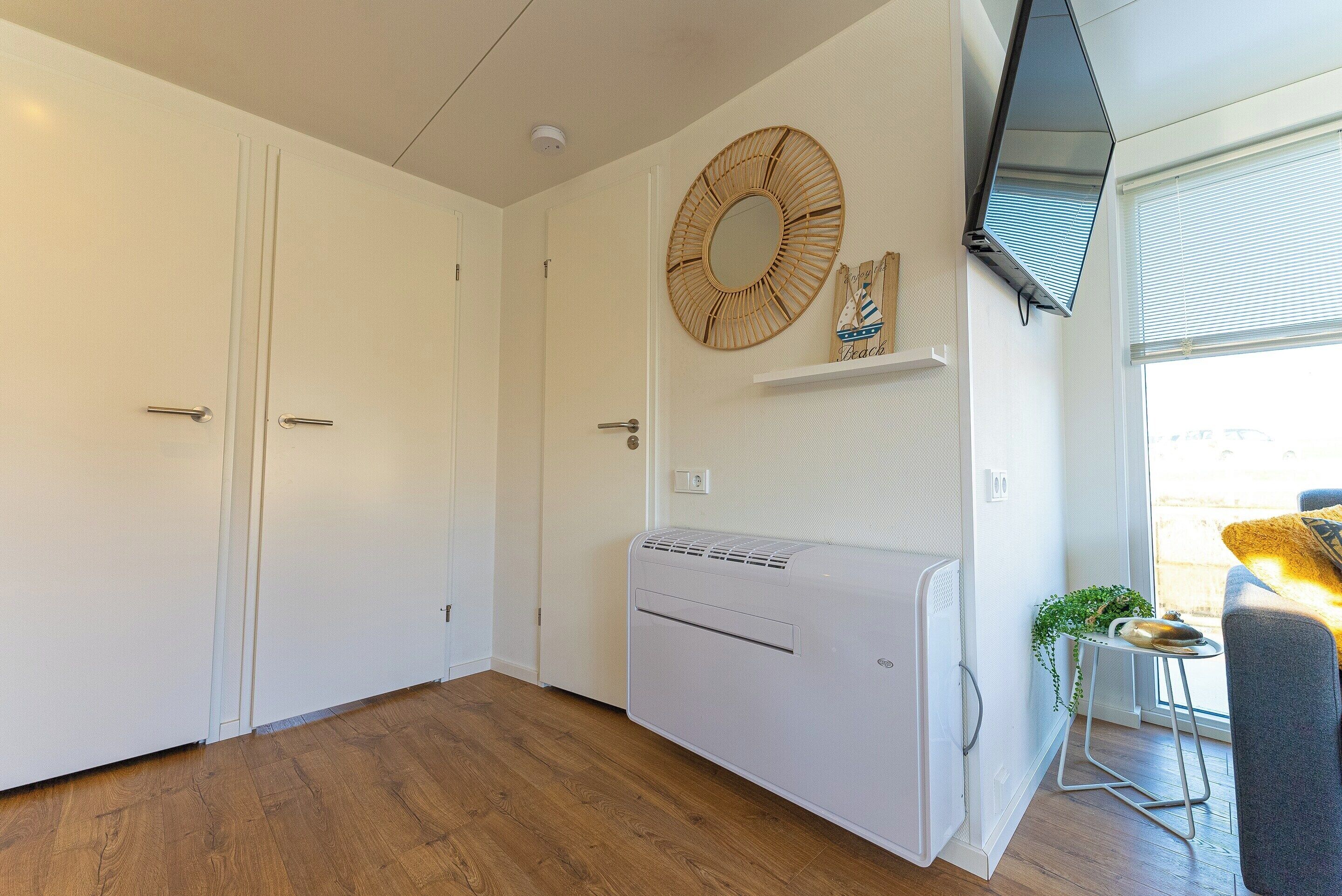 Ein Zimmer mit großem Schrank, Wandklimaanlage und Fenster mit Rollo.