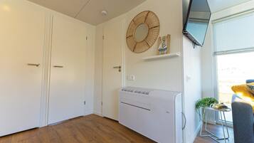 Ein Zimmer mit großem Schrank, Wandklimaanlage und Fenster mit Rollo.