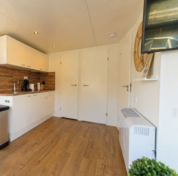 A modern kitchen with white cabinets, wooden flooring, and a built-in stove.