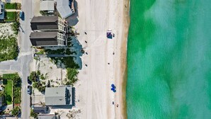 Ein Luftbild eines Anwesens am Strand, mit einer Straße, Gebäuden und freiem Blick auf den Ozean.