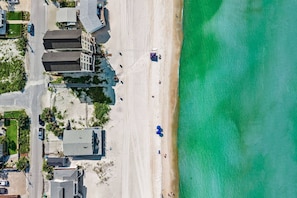 Ein Luftbild eines Anwesens am Strand, mit einer Straße, Gebäuden und freiem Blick auf den Ozean.