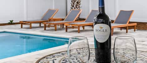 Escena junto a la piscina con una botella de Bogle Family Cabernet Sauvignon, dos copas y sillones de descanso.
