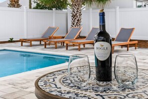 Ein Poolbereich mit einer Flasche Bogle Family Cabernet Sauvignon, zwei Gläsern und Liegestühlen.