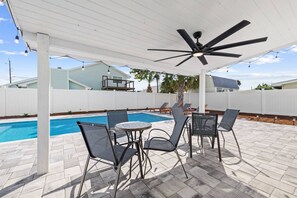 An outdoor patio with a pool, surrounded by a white fence, featuring a ceiling fan and string lights. - New Listing w/ Limited Time Discounted Rates! Sun, Sand & Your Own Backyard Oasis w/ Private Pool! (Panama City Beach)