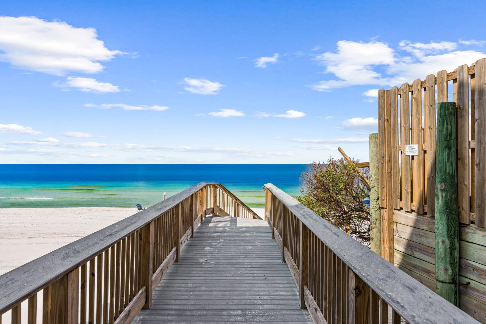 Una pasarela de madera que conduce a una playa, con vista despejada al océano.
