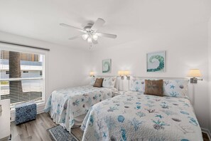 Ein Schlafzimmer mit zwei Betten, einem Deckenventilator und Bildern an den Wänden.